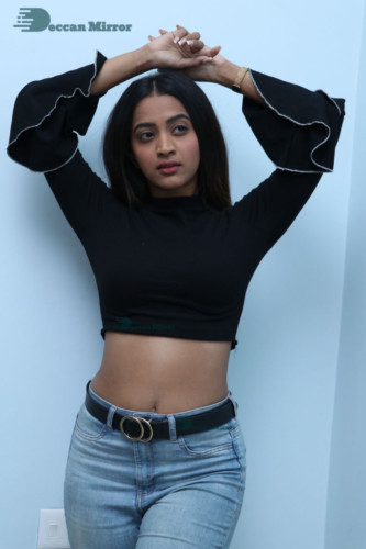 Actress Sruthi Shetty in a black top and blue jeans