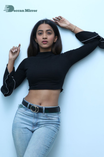 Actress Sruthi Shetty in a black top and blue jeans