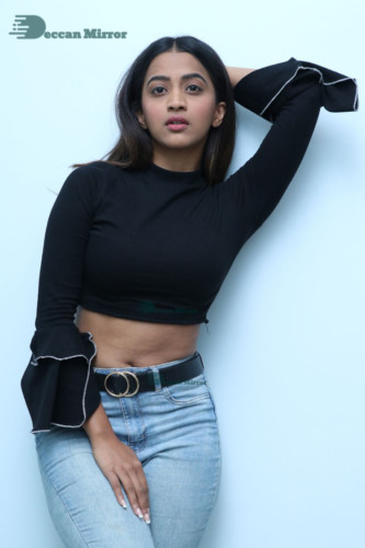 Actress Sruthi Shetty in a black top and blue jeans