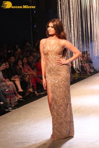 Tara Sutaria wearing a gold color dress for her ramp walk at Bombay Times Fashion Week