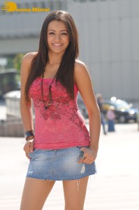 Trisha in a pink top and denim mini skirt on location for a film shoot