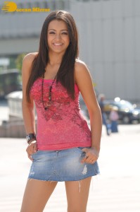 Trisha in a pink top and denim mini skirt on location for a film shoot